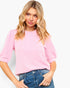 A woman wearing a light pink ribbed short-sleeve top and blue jeans, photographed against a clean white studio background.