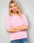 Woman wearing a pink sweater with puffed sleeves against a gray background