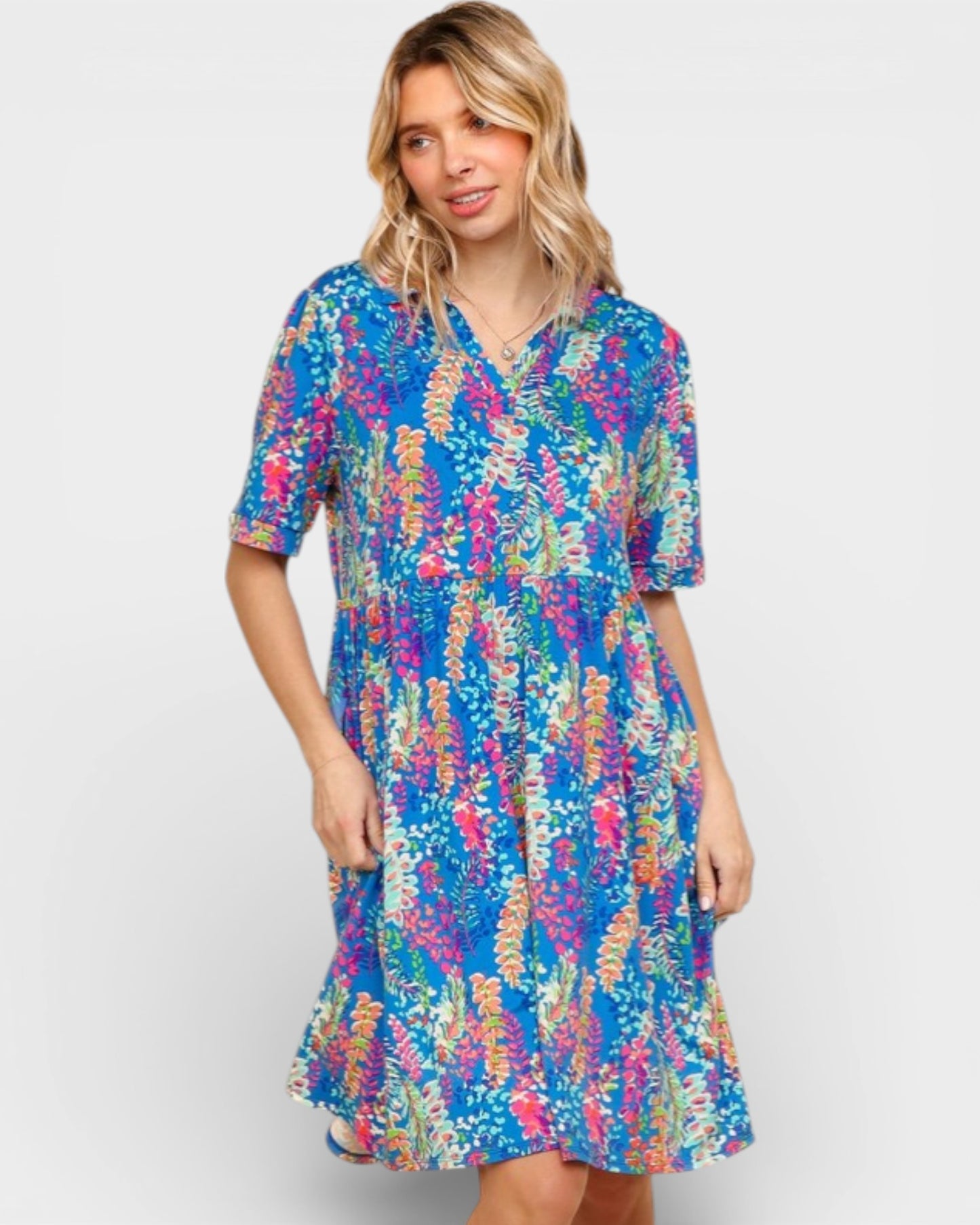 Woman wearing a colorful patterned dress on a plain background