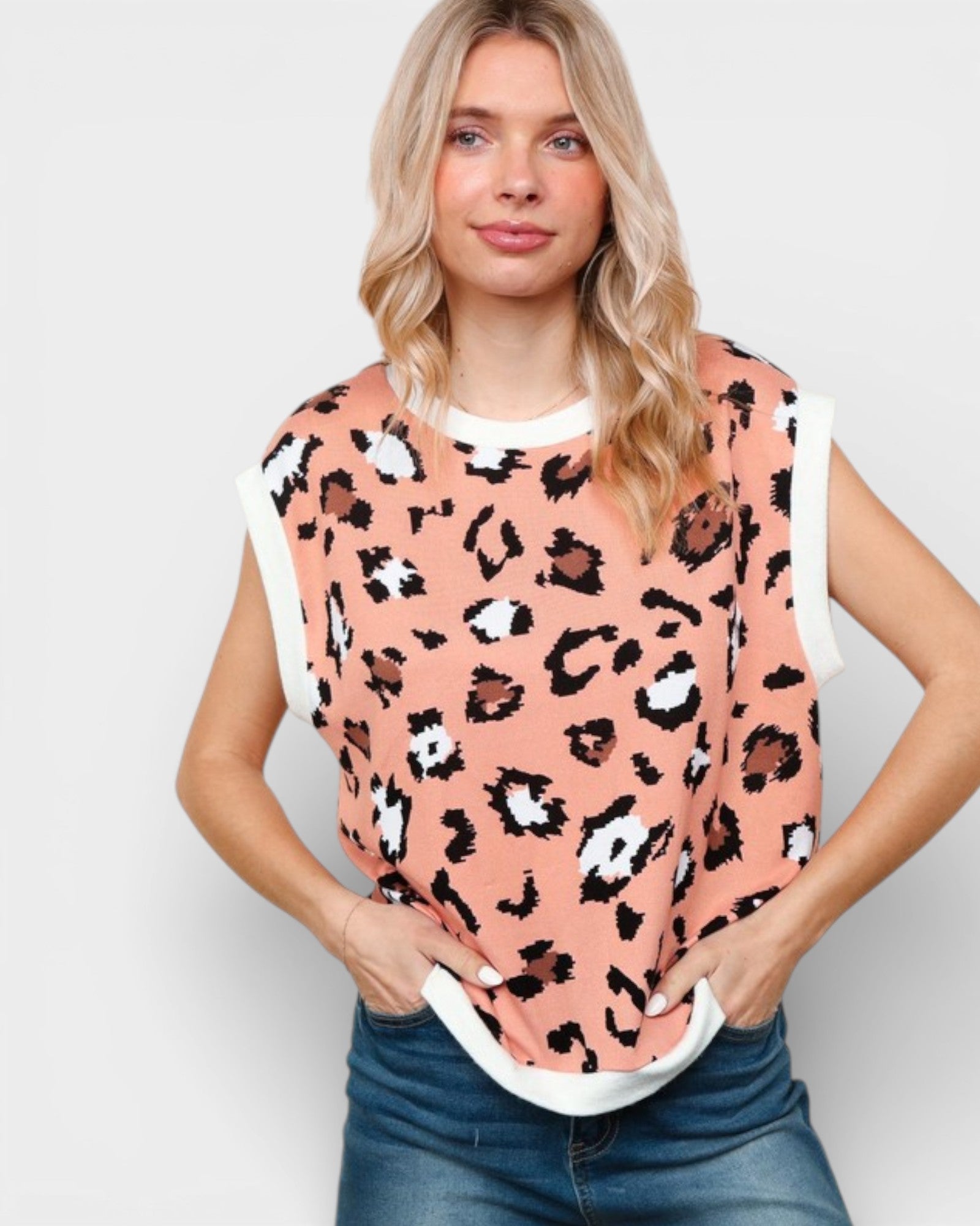 Woman wearing a pink leopard print top with white sleeves against a plain background