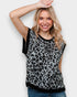 Woman wearing a leopard print sleeveless top against a plain background
