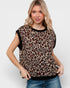 Woman wearing a leopard print top with black trim on a white background