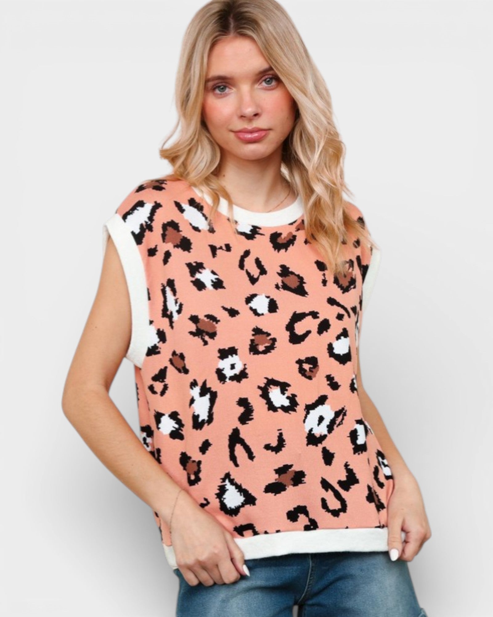 Woman wearing a sleeveless top with leopard print on a plain background