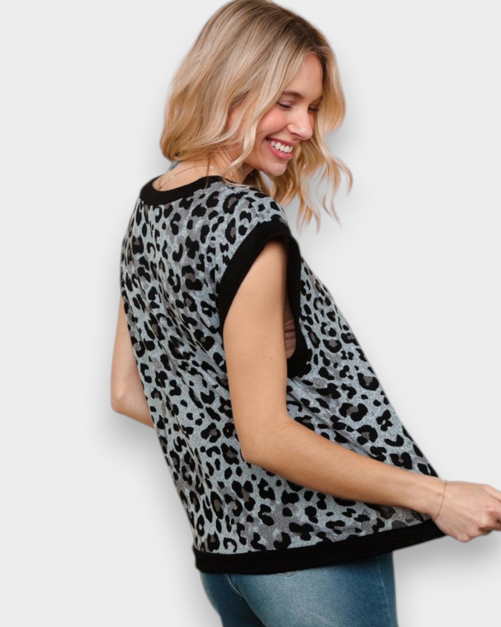 Woman wearing a leopard print top with black trim on a white background