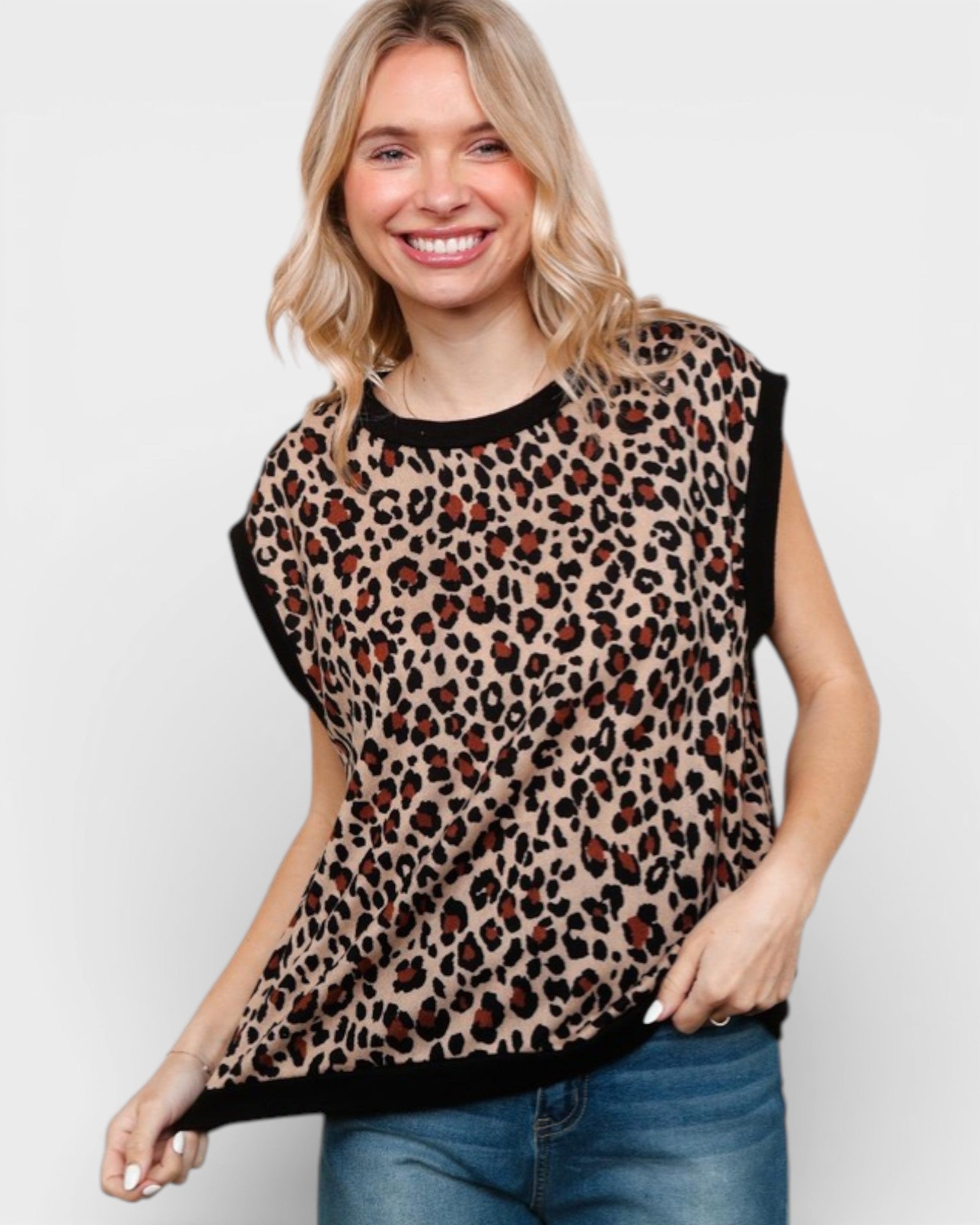 Woman wearing a leopard print top with black trim on a plain background