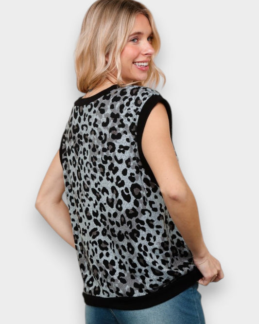 Woman wearing a sleeveless top with a leopard print pattern on a plain background