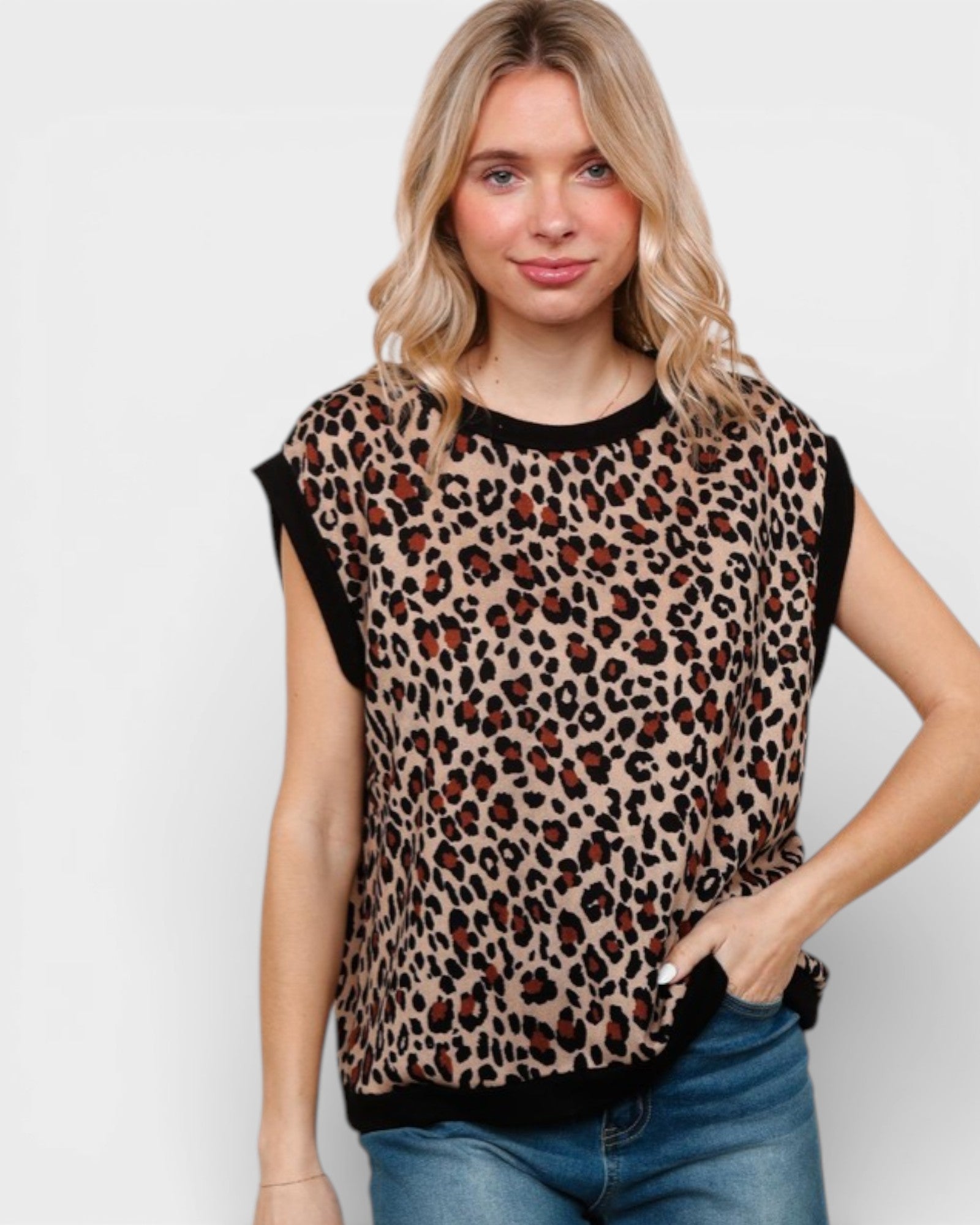 Woman wearing a leopard print top with black trim on a plain background