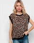 Woman wearing a leopard print top with black trim on a plain background