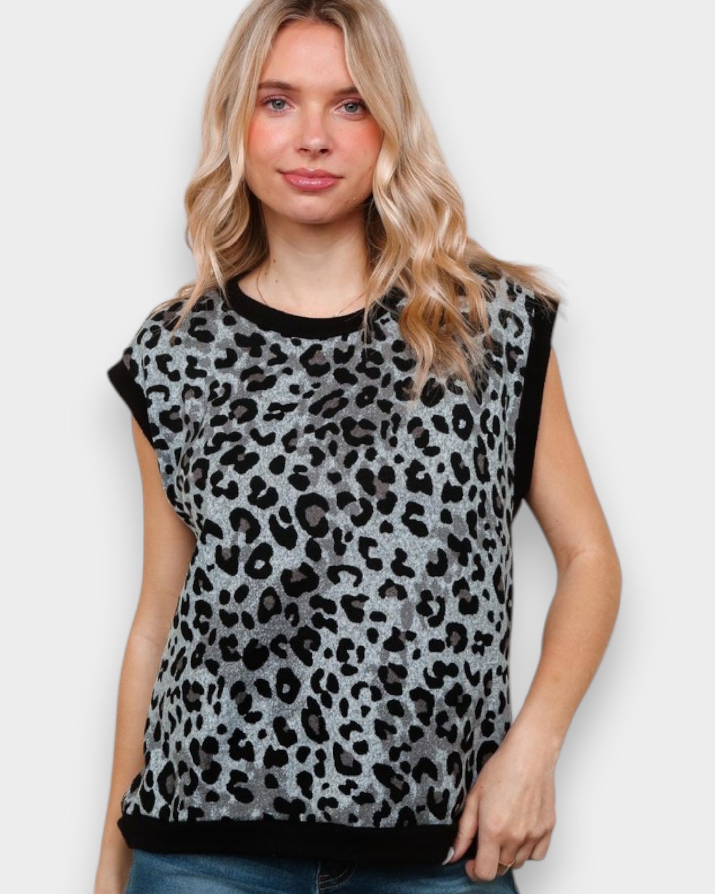 Woman wearing a sleeveless leopard print top against a plain background