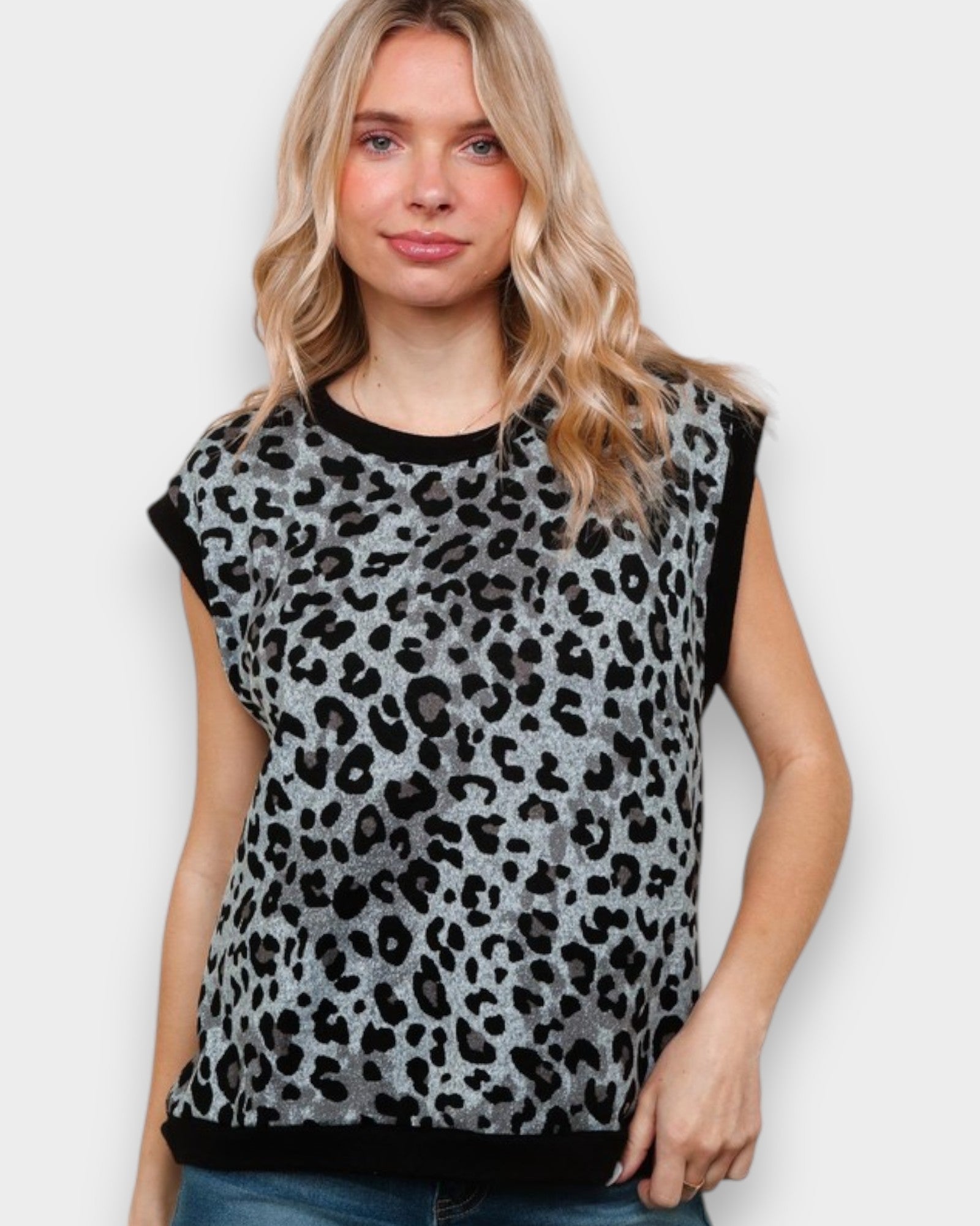 Woman wearing a sleeveless leopard print top against a plain background
