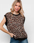 Woman wearing a leopard print top with black sleeves against a plain background