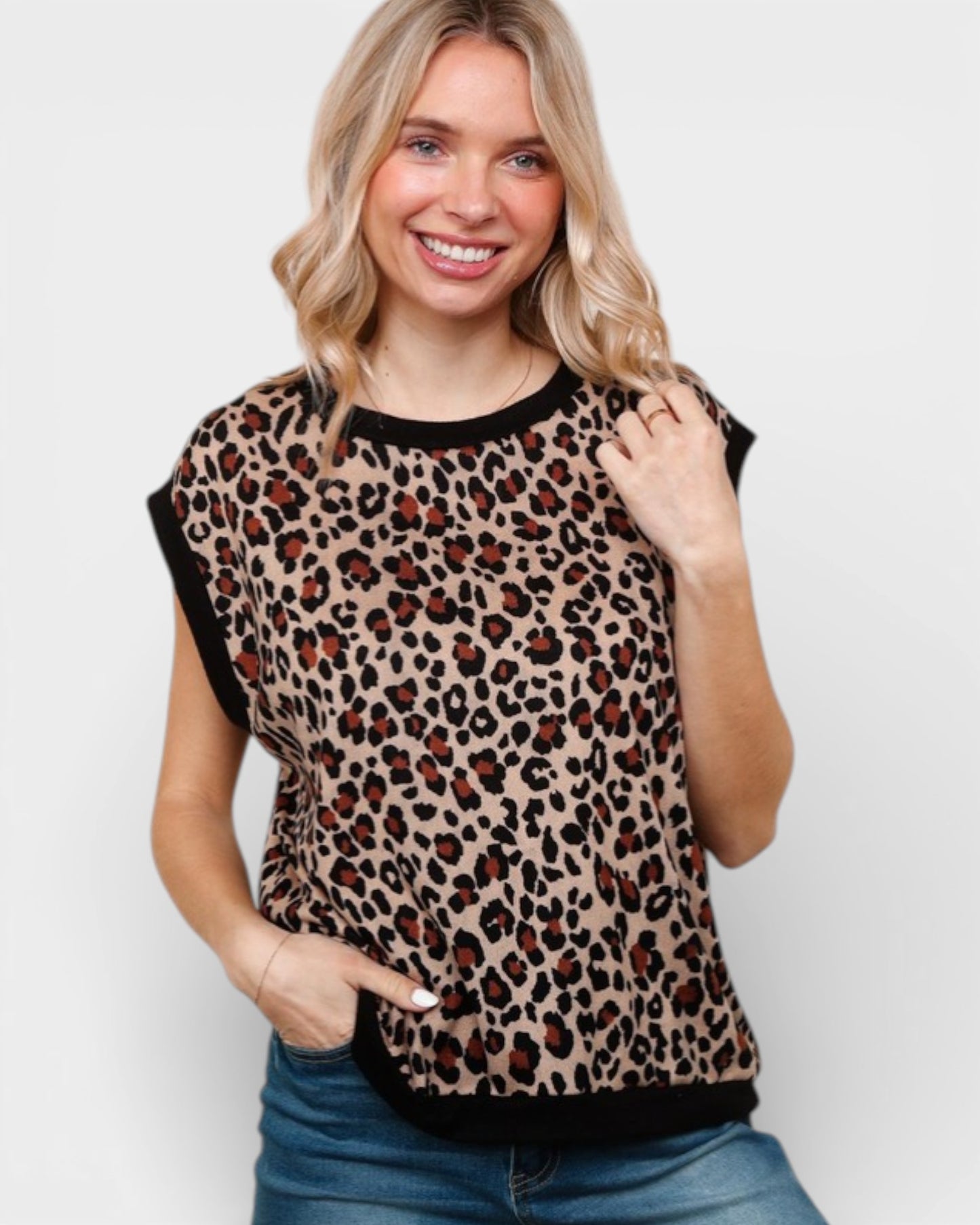Woman wearing a leopard print top with black trim on a plain background