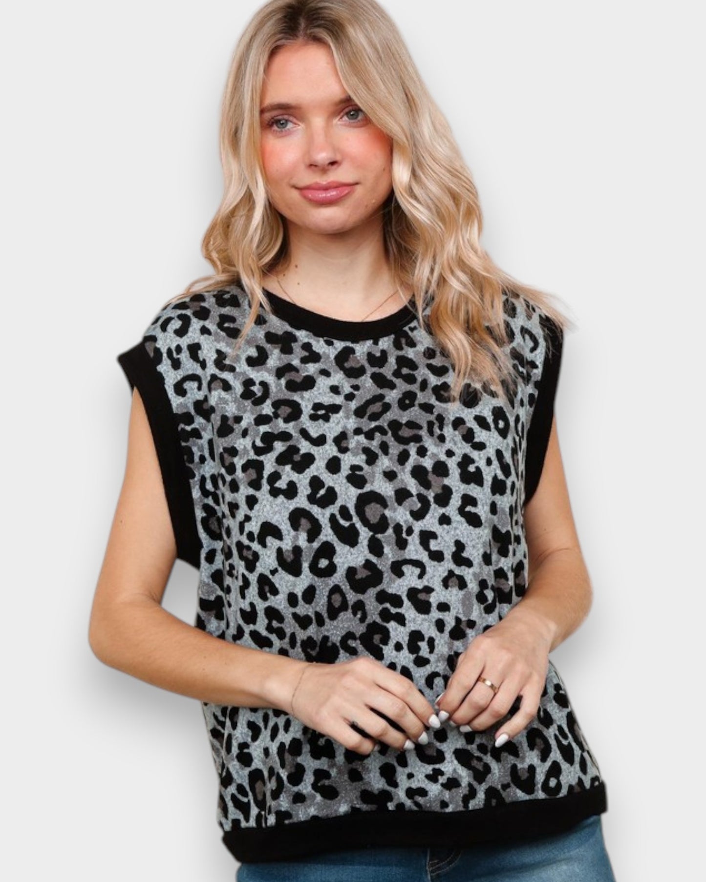 Woman wearing a leopard print top with black sleeves on a white background