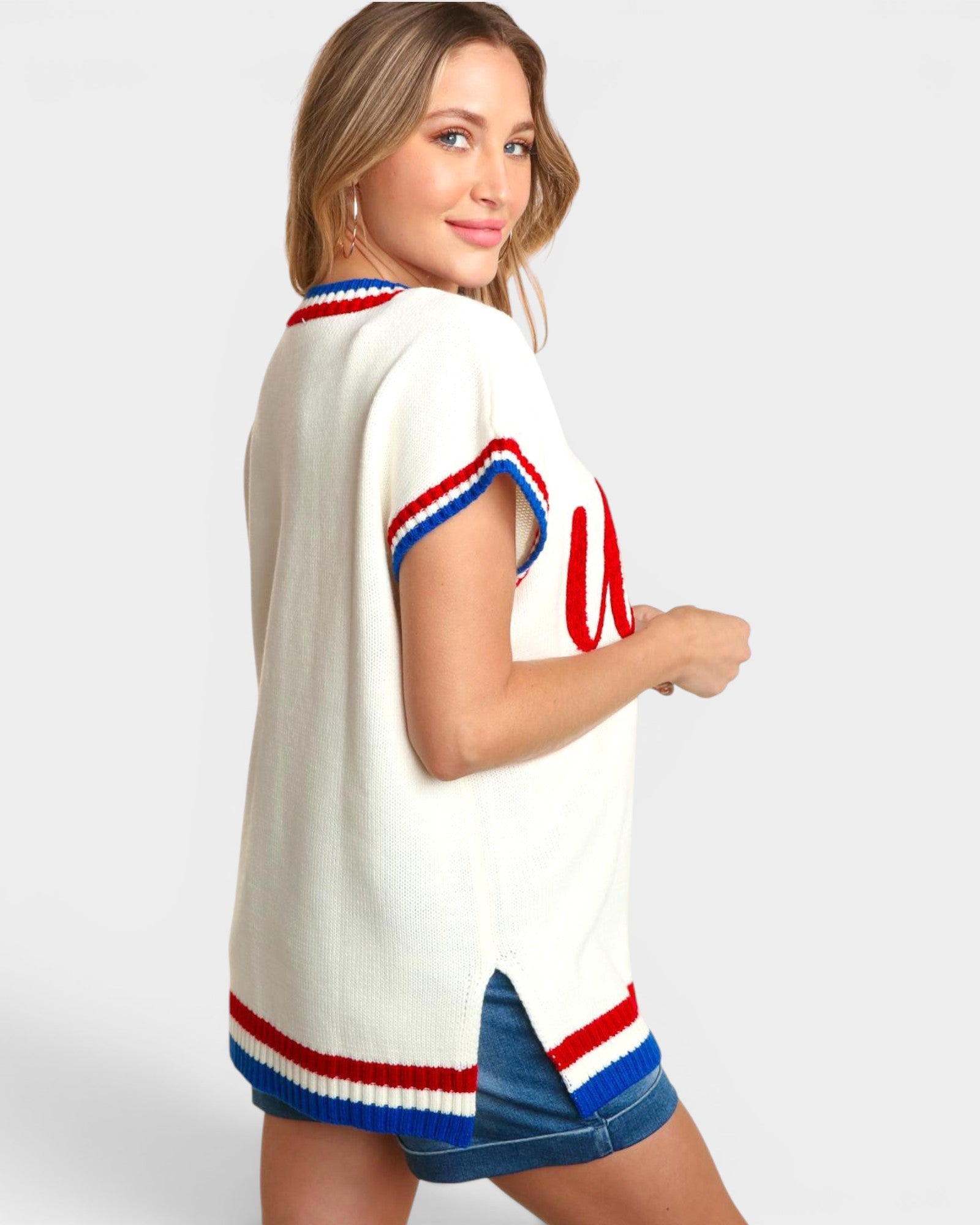Woman wearing a white sweater with red and blue accents on a plain background