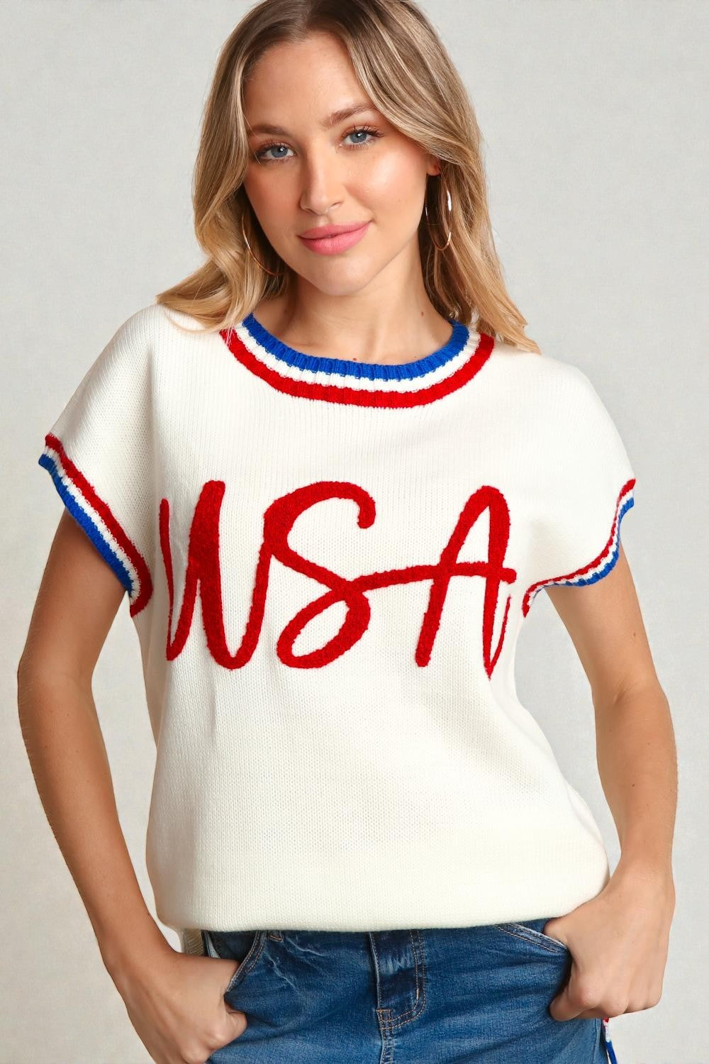 Woman wearing a white sweater with 'USA' in red and blue on a plain background