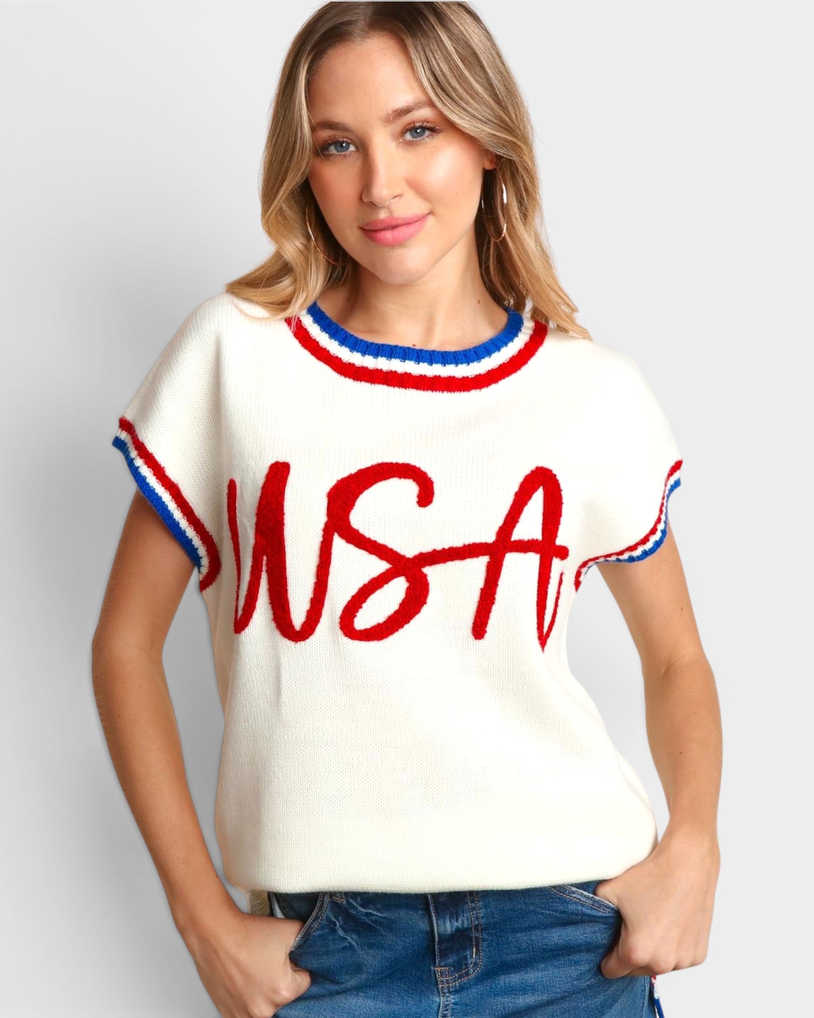Woman wearing a white sweater with red and blue accents and 'USA' text on a plain background