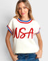 Woman wearing a white sweater with red and blue accents and 'USA' text on a plain background