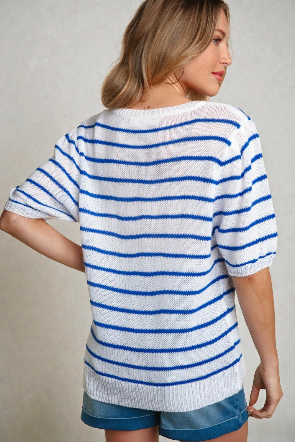Woman wearing a white and blue striped shirt with a neutral background
