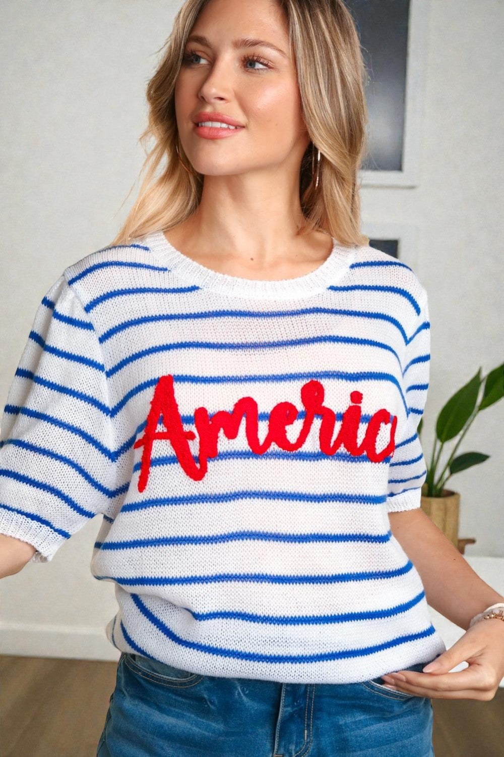 Woman wearing a white and blue striped sweater with 'America' printed in red.