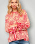 Woman wearing a red and pink patterned blouse with rolled-up sleeves against a gray background