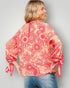 Woman wearing a red floral blouse with tied sleeves on a gray background