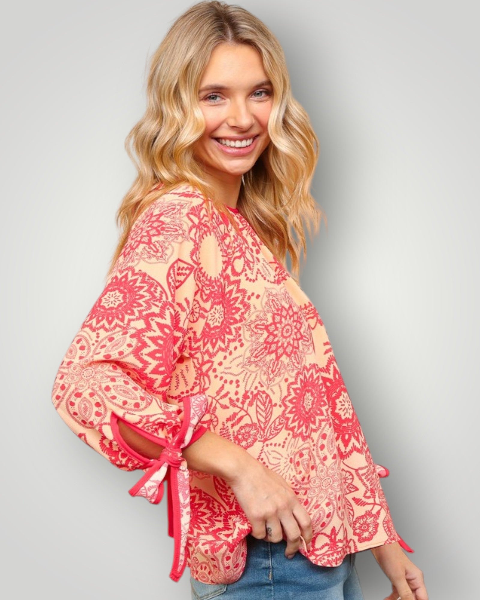 Woman wearing a red and pink floral kimono-style top against a gray background