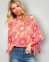 Woman wearing a red and pink floral patterned top with blue jeans on a gray background