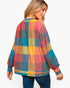 A woman shown from the back wearing a loose long-sleeve plaid sweater with a multicolor check pattern in blue, red, yellow, and gray, paired with blue jeans against a light gray studio background.