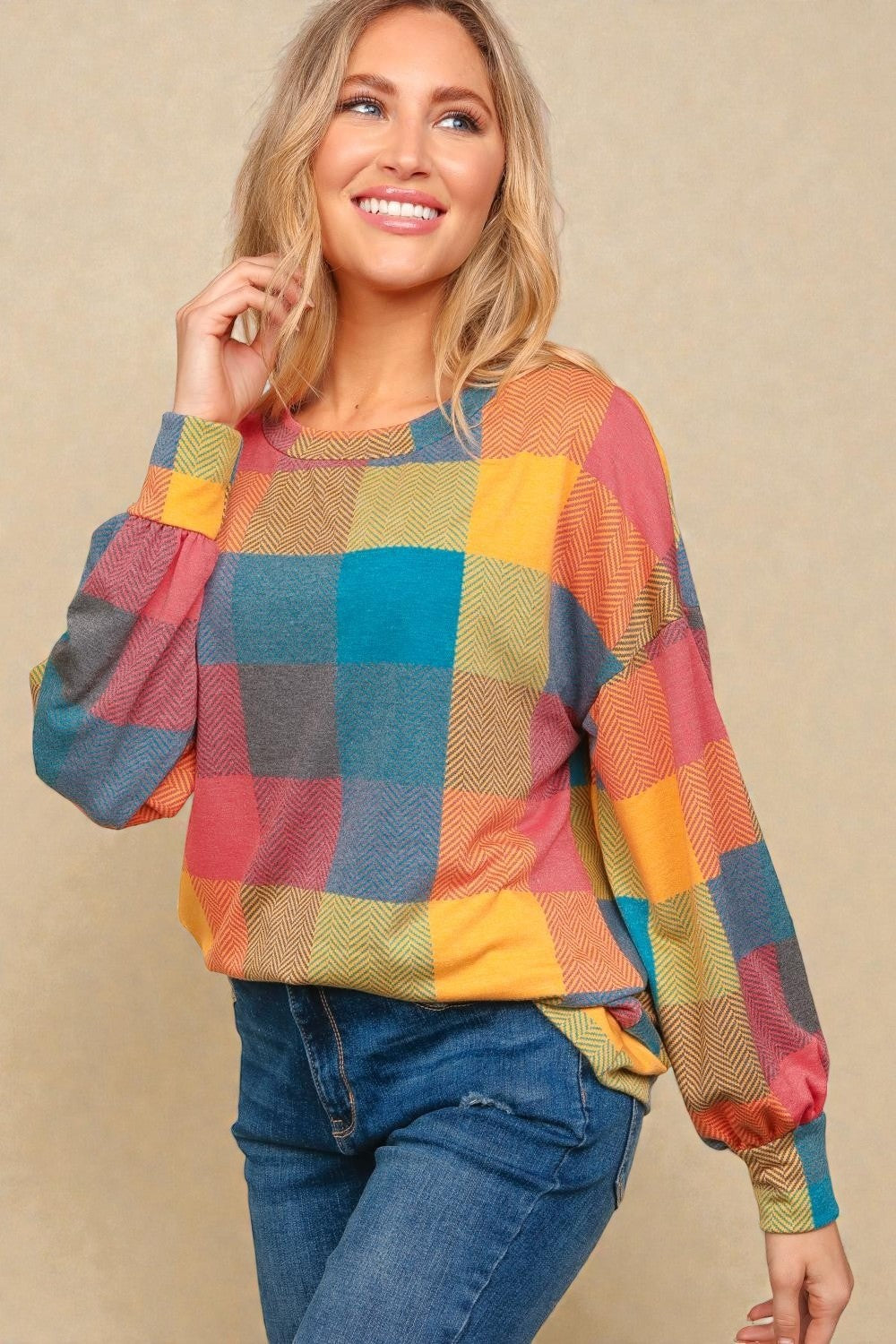 Woman wearing a colorful checkered sweater against a beige background