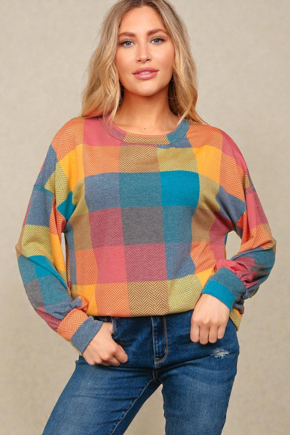 Woman wearing a colorful checkered sweater against a beige background