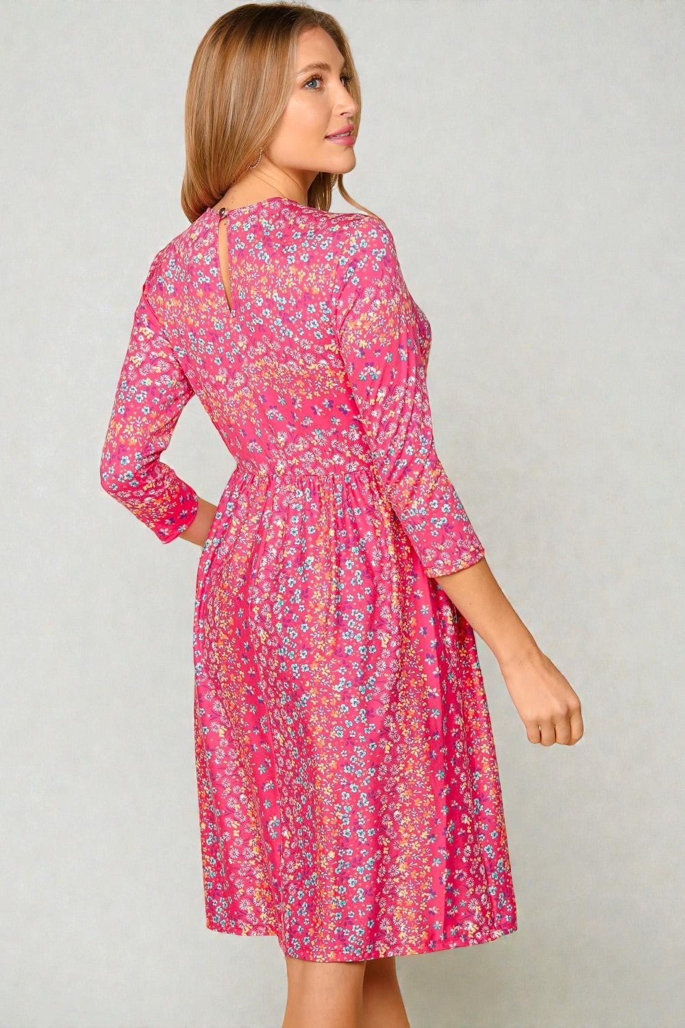 Woman wearing a pink floral dress against a plain background