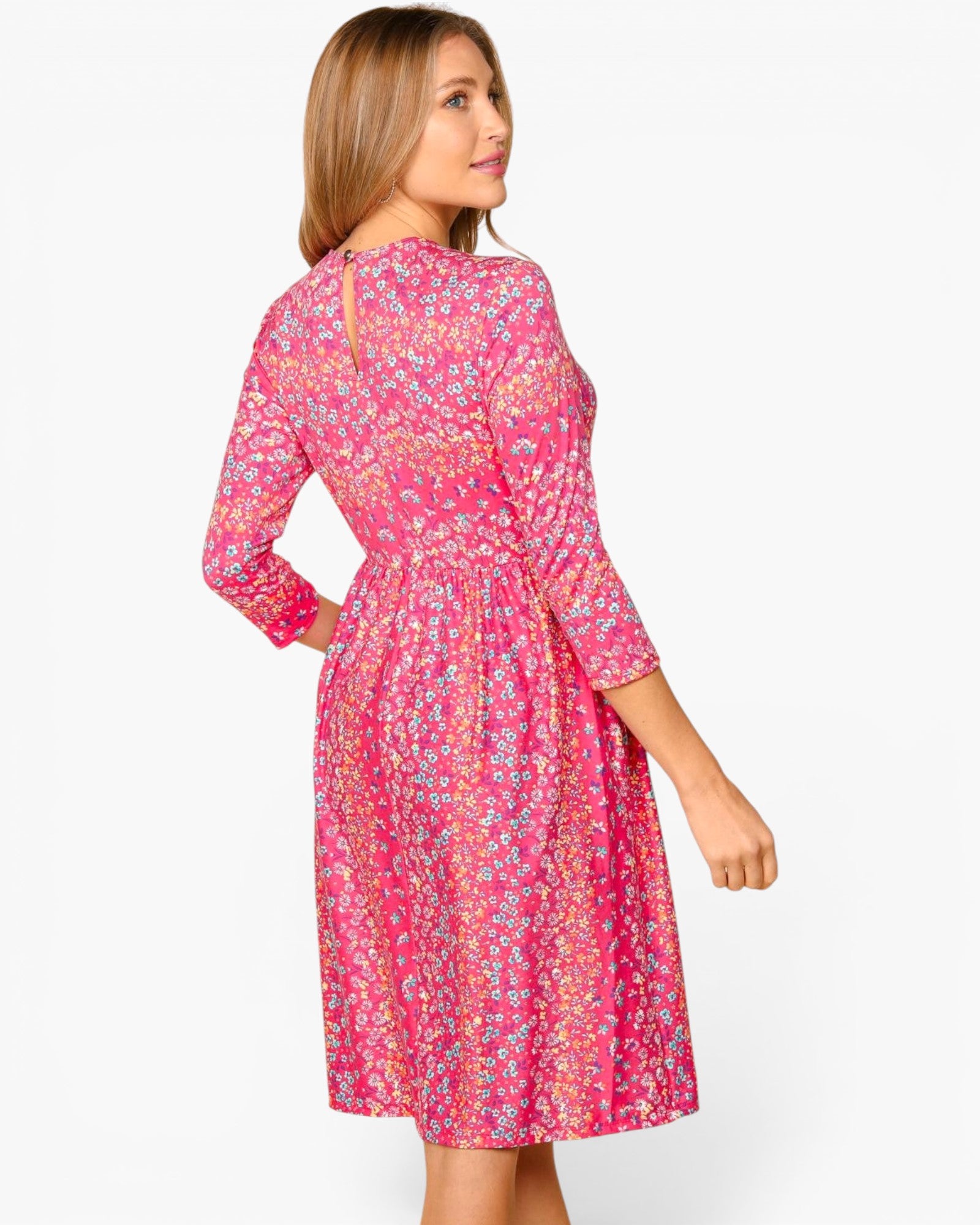 A woman wearing a pink floral long-sleeve dress, shown from the back and side against a plain white studio background.
