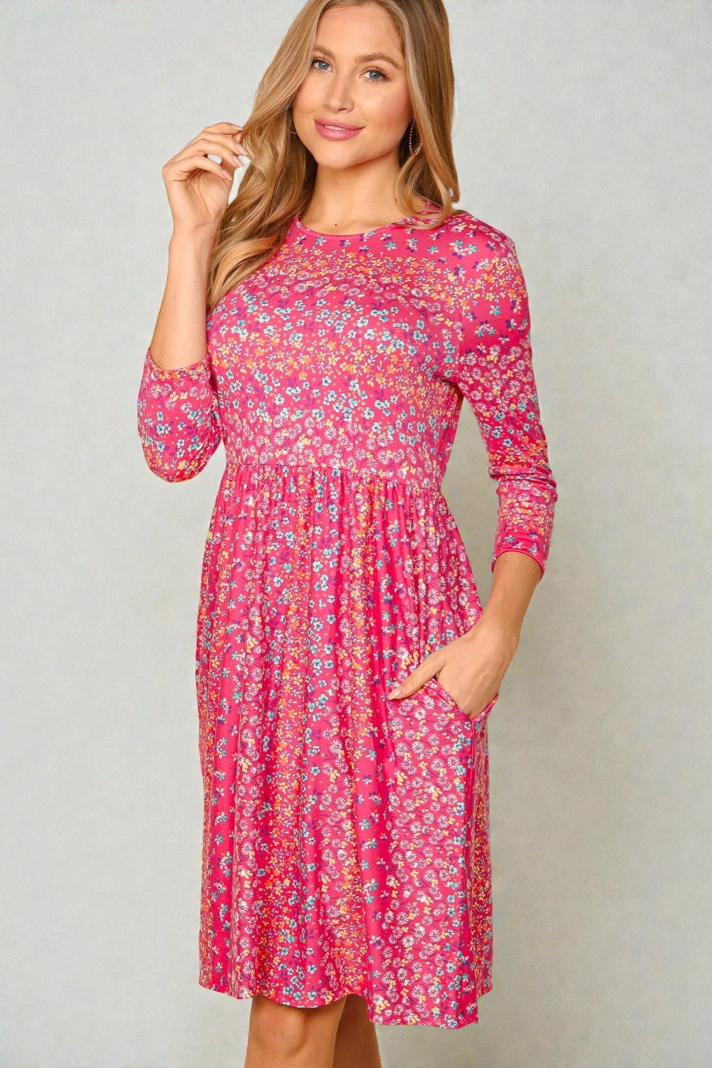 Woman wearing a pink floral dress against a plain background