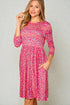 Woman wearing a pink floral dress against a plain background