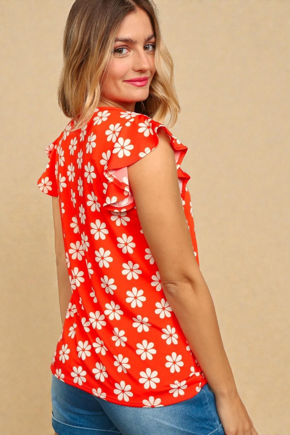 Woman wearing a red floral blouse against a beige background