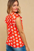 Woman wearing a red floral blouse against a beige background