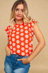 Woman wearing a red floral top and blue jeans against a beige background