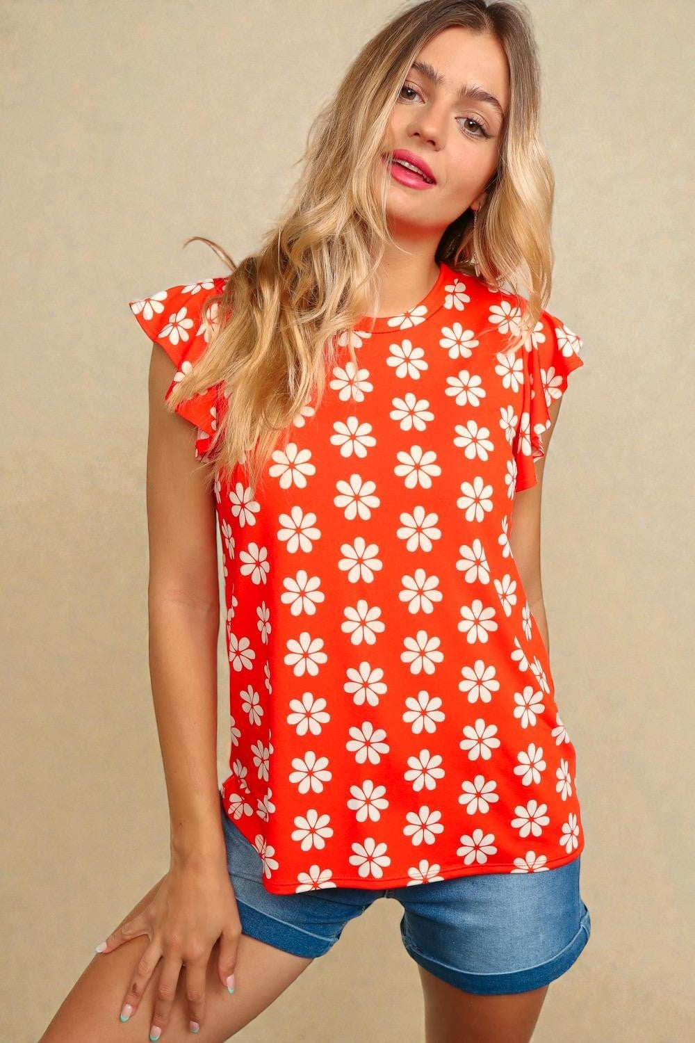 Woman wearing a red sleeveless top with white floral pattern on a beige background