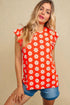 Woman wearing a red sleeveless top with white floral pattern on a beige background