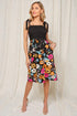 Woman wearing a black top and colorful floral skirt against a white background