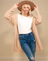 Woman wearing a beige cardigan, white shirt, blue jeans, and a brown hat on a beige background
