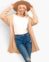 A woman modeling a beige open-front knit cardigan over a white t-shirt and blue jeans, wearing a wide-brim tan hat against a light gray background.