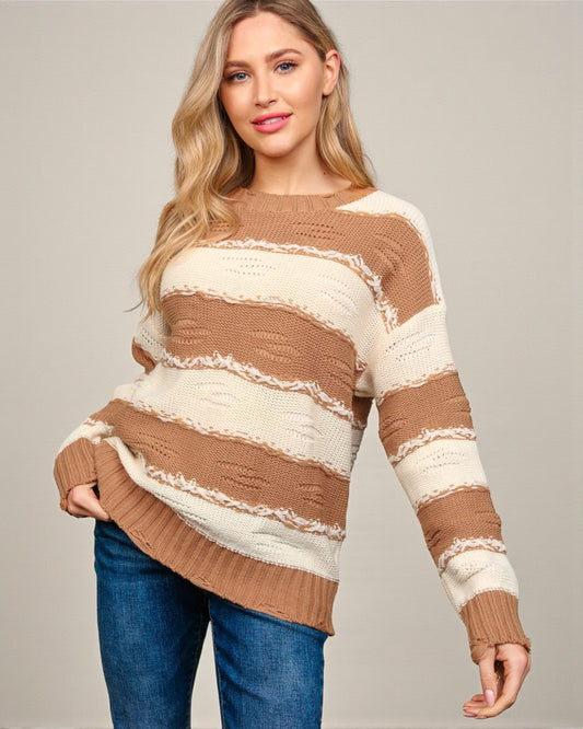 Woman wearing a brown and white striped sweater against a plain background