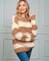Woman wearing a brown and beige striped sweater against a gray wall.
