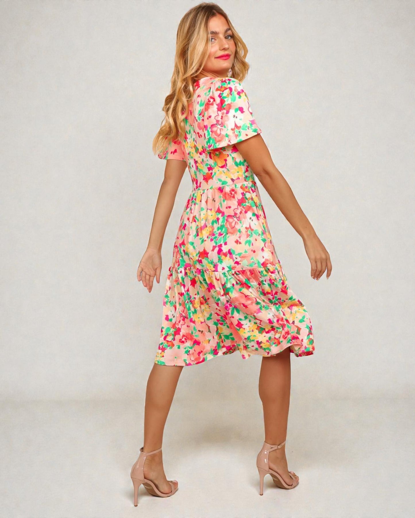 Woman wearing a colorful floral dress on a plain background