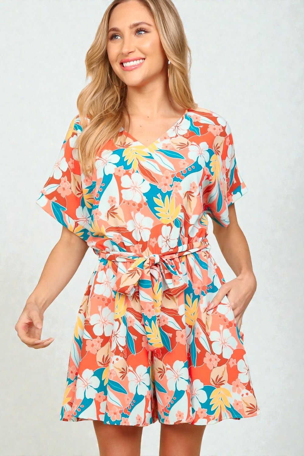 Woman wearing a colorful floral romper on a white background