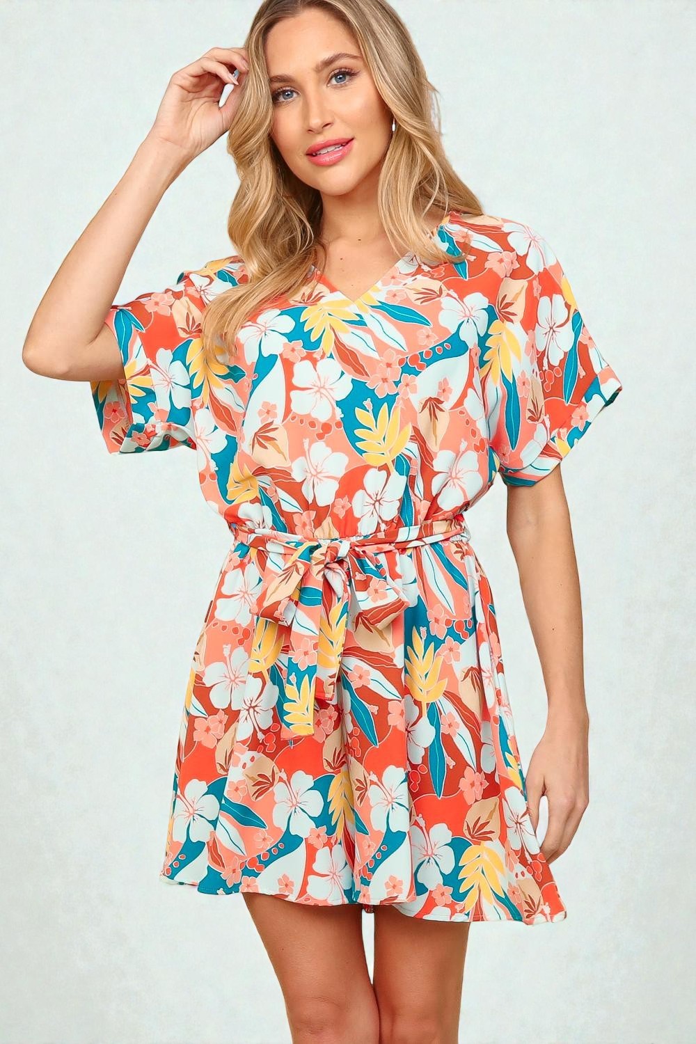 Woman wearing a colorful floral romper on a white background