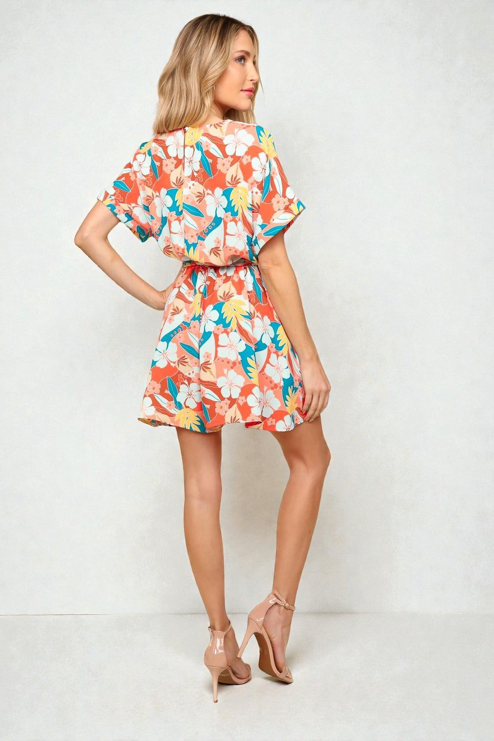 Woman wearing a colorful floral romper on a white background