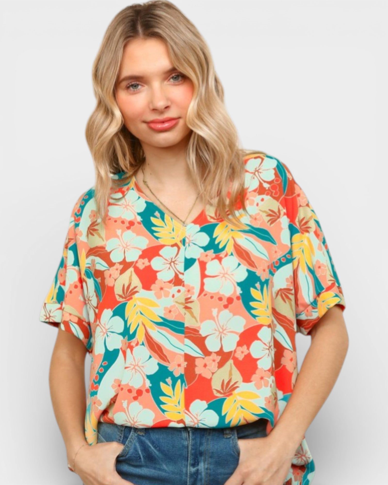 Woman wearing a colorful floral blouse against a plain background