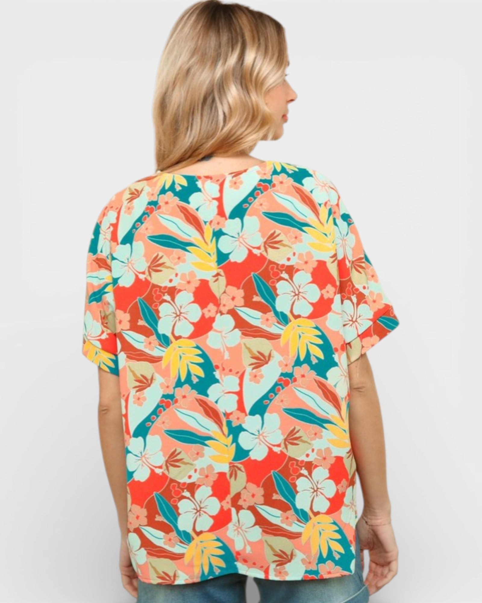 Woman wearing a colorful floral patterned shirt on a plain background